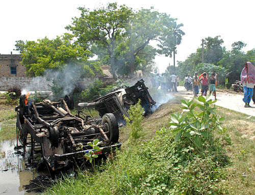 People walk past overturned vehicles that was burnt by protesters as they campaign against contaminated meals that were given to children, at Chapra in the eastern Indian state of Bihar July 17, 2013. At least 25 Indian children died and dozens needed hospital treatment after apparently being poisoned by a school meal on Tuesday, sparking violent protests and angry allegations of blame. The school, at Mashrakh village in the district of Chapra, provided free meals under the Mid-Day Meal Scheme, the world's largest school feeding programme involving 120 million children. Medical teams treating the children said they suspected the food had been contaminated with insecticide. REUTERS