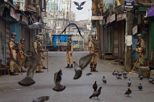 Indian paramilitary soldiers stand guard at a closed market area during curfew in Srinagar, India, Friday, July 19, 2013. Government forces in the Indian portion of Kashmir on Thursday fatally shot four villagers and wounded 25 others who were protesting the alleged desecration of the Muslim holy book by border guards, police said. (AP Photo