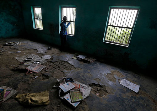 A boy stands inside a classroom near books and steel plates of children, who consumed contaminated meals given to them at a school on Tuesday, at Chapra district in the eastern Indian state of Bihar July 18, 2013. The Indian government announced on Thursday it would set up an inquiry into the quality of food given to school pupils in a nationwide free meal scheme after at least 23 children died in one of the deadliest outbreaks of mass poisoning in years. REUTERS