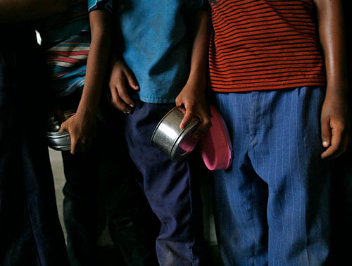 School boys carry their tiffin boxes as they wait to receive their free mid-day meal, distributed by a government-run primary school, in New Delhi