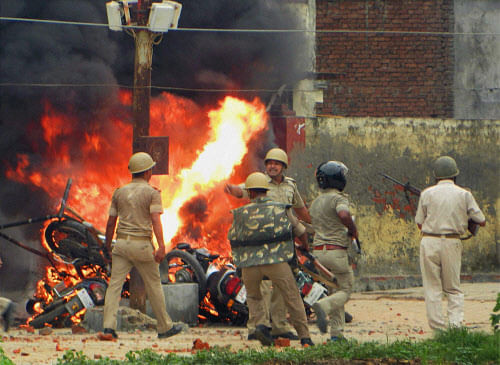Police men move past burning motorcycles which torched by violent mob on Friday after BSP MLA Sarvesh Singh Seepu was shot dead with guard. PTI Photo