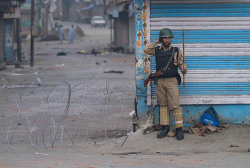 A paramilitary soldier stands guard in a deserted market during curfew in Srinagar, India, Friday, July 19, 2013. Government forces in the Indian portion of Kashmir on Thursday fatally shot four villagers and wounded 25 others who were protesting the alleged desecration of the Muslim holy book by border guards, police said. AP photo