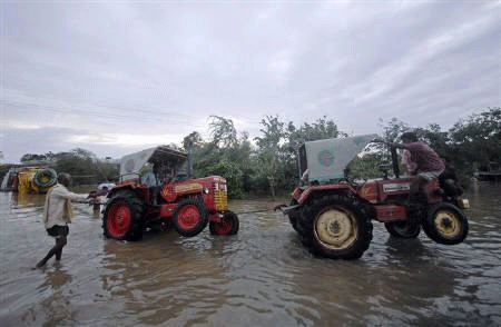 Tractors move through a flooded village in Andhra Pradesh, May 21, 2010. Reuters