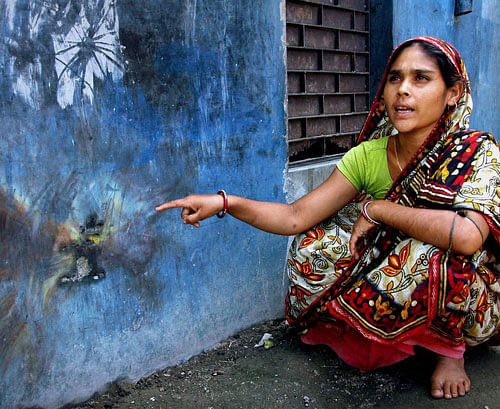 : A woman pointing to the bombing mark on the wall after the political clash took place ahead of 4th phase of Panchayat polls in Murshidabad district of West Bengal on Sunday. PTI Photo