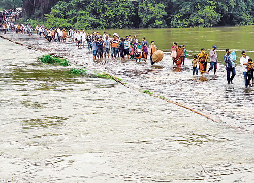 Braving floods: People cross the bridge across River Kumaradhara to reach Kukke Subramanya on Sunday. (Below) Movement of vehicles to Horanadu was affected after the road caved in at Channekallu in Koppa taluk of Chikmagalur district. dh photos