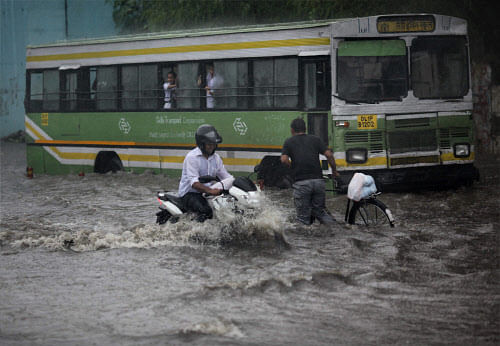 A motorcyclist wades through a waterlogged road after heavy shower in New Delhi on Saturday. PTI Photo
