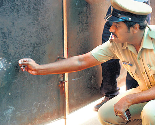 Triggering panic: A police officer inspects the spot where the gunshot fired accidentally by a security guard hit, in Koramangala on Wednesday. dh photo