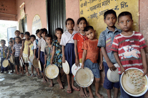 School children queue up for mid-day meal at a government school in Patna on Thursday. PTI Photo