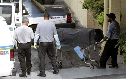Miami-Dade morgue workers carry out a body out at the scene of a fatal shooting in Hialeah, Fla., Saturday, July 27, 2013. A gunman holding hostages inside the apartment complex killed six people before being shot to death by a SWAT team that stormed the building early Saturday following an hours-long standoff, police said. AP photo
