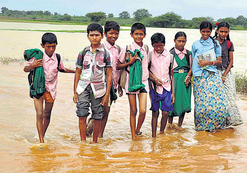 Cut-off: Students are forced to stay at home as the only road that links their village with their school in Marola, Haveri district is submerged. DH Photo