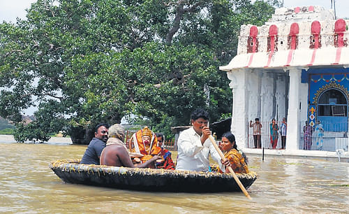 Filled to the brim: An idol of Anjaneya in Hampi being moved to a safer place as River Tungabhadra is overflowing. (Left) People travel by boats, the lone mode of transport on either side of the border between Karnataka and Maharashtra during the rainy season. DH Photos