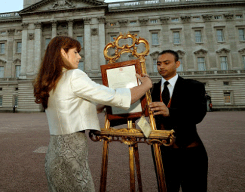 The Queen's Press Secretary Ailsa Anderson with Badar Azim, a footman, places an official document to announce the birth of a baby boy, at 4.24pm to the Duke and Duchess of Cambridge at St Mary's Hospital, in the forecourt of Buckingham Palace in London Monday July 22, 2013. The child is now third in line to the British throne. (AP Photo