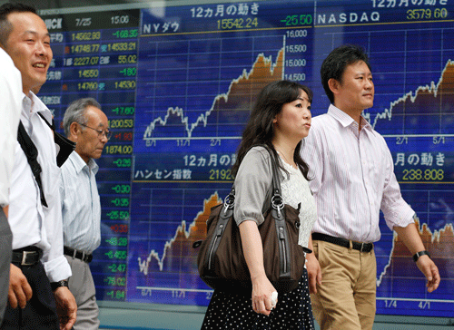 People walk by an electronic stock board of a securities firm in Tokyo. AP