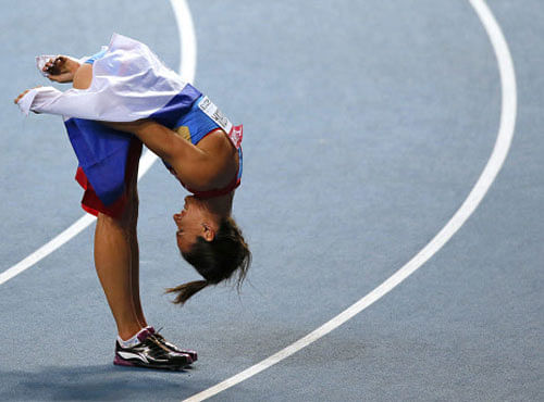 Yelena Isinbayeva of Russia bows to thank the spectators as she celebrates with her national flag after winning gold in the women's pole vault final during the IAAF World Athletics Championships at the Luzhniki stadium in Moscow August 13, 2013. REUTERS