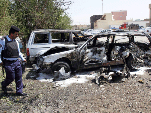 A policeman inspects a damaged vehicle at the site of a bomb attack in Kirkuk, 250 km (155 miles) north of Baghdad, August 22, 2013. Four people were wounded in the attack, police said. REUTERS