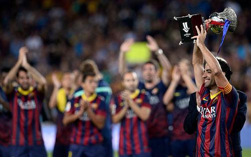 FC Barcelona's Xavi Hernandez, right, holds the trophy after winning the Spanish Super Cup against Atletico Madrid at the Camp Nou stadium in Barcelona, Spain, Wednesday, Aug. 28, 2013. (AP Photo
