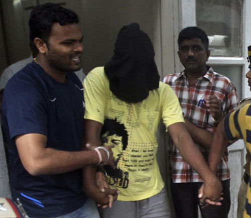 Police officials escort an accused, head covered with black cloth, in the gang rape of a photojournalist after producing him before a court in Mumbai. AP Photo