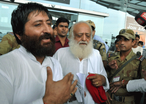 Asaram Bapu and his son Narayan Sai coming out from Raja Bhoj Airport after they missed the flight, in Bhopal on Friday. PTI Photo