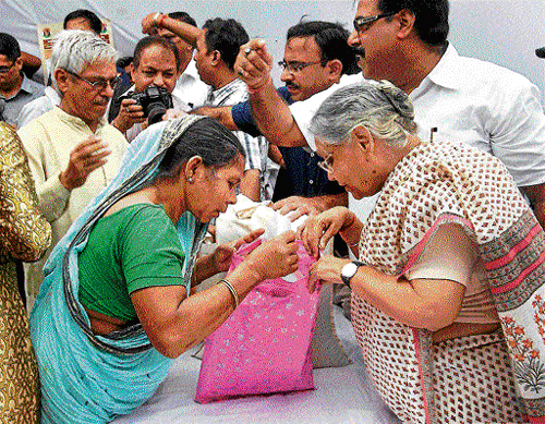 Chief Minister Sheila Dikshit gives foodgrains in Delhi under food security scheme. dh photo