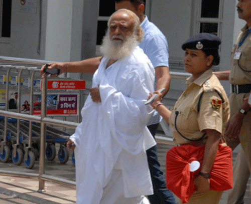 Police escort spiritual leader Asaram Bapu (L) outside an airport after his arrest in Jodhpur, in India's desert state of Rajasthan September 1, 2013. Police arrested Bapu from India's central Madhya Pradesh state late on Saturday night and transited him to neighbouring Rajasthan for further questioning on charges of sexual assault on a minor. REUTERS