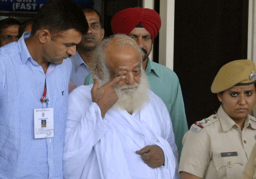 Controversial spiritual guru Asaram Bapu, center in white, is brought for interrogation by police at the Jodhpur airport in Jodhpur, India, Sunday, Sept.1, 2013. Bapu was arrested in central India early Sunday on a rape charge filed by a teen-age girl in the northwestern Indian state of Rajasthan, police said. The case is the latest in a series of high-profile rape cases in India that have fueled public protests and raised questions about how police handle the cases and treat the victims. AP photo