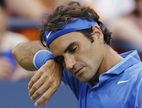 Roger Federer, of Switzerland, wipes sweat from his face between points during his match against Tommy Robredo, of Spain, during the fourth round of the 2013 U.S. Open tennis tournament, Monday, Sept. 2, 2013, in New York. (AP Photo)
