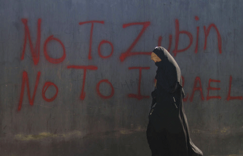 A woman walks past graffiti against a concert by renowned orchestra conductor Zubin Mehta in Srinagar, India, Friday, Sept. 6, 2013. Kashmiri separatists have called for a strike on Sept. 7 to protest against a concert by Mehta in Srinagar, accusing the event of distracting the public away from the problems that Kashmir faces. AP photo