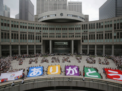 A message reading 'THANK YOU' (top row) made up by people standing in formation and banners reading 'Arigato (Thank You)' are displayed during an event celebrating Tokyo being chosen to host the 2020 Olympic Games, at Tokyo Metropolitan Government Building in Tokyo September 8, 2013. Tokyo was awarded the 2020 summer Olympic Games on Saturday, beating Istanbul in a head-to-head vote after Japanese Prime Minister Shinzo Abe delivered a charismatic plea to the International Olympic Committee and promised Japan's crippled nuclear plant was 'under control.' REUTERS