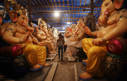 An artisan walks past the idols of Hindu elephant god Ganesh, the deity of prosperity, kept inside a workshop in Mumbai September 3, 2013. The idols will be paraded through the streets in a procession during the Ganesh Chaturthi festival, accompanied by dancing and singing. They will then be immersed in a river or the sea symbolizing a ritual send-off of Ganesh's journey towards his abode in 'Kailash', while taking away with him the misfortunes of all mankind. The festival will be celebrated on September 9. REUTERS