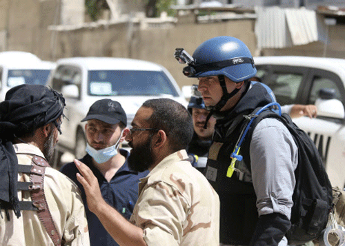 A Free Syrian Army fighter talks to U.N. chemical weapons experts during their visit to one of the sites of an alleged chemical weapons attack in the Ain Tarma neighbourhood of Damascus August 29, 2013.The team of U.N. experts left their Damascus hotel for a third day of on-site investigations into apparent chemical weapons attacks on the outskirts of the capital. Activists and doctors in rebel-held areas said the six-car U.N. convoy was scheduled to visit the scene of strikes in the eastern Ghouta suburbs. REUTERS