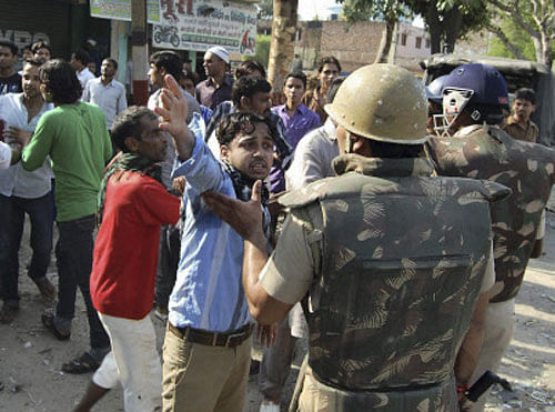 In this Saturday, Sept. 9, 2013 photo, people argue with Indian policemen during curfew hours following riots and clashes between two communities in Muzaffarnagar, in the Indian state of Uttar Pradesh. Hundreds of troops have been deployed to quell deadly riots and clashes between Hindus and Muslims sparked by the killing of three villagers who had objected when a young woman was being harassed in northern India. Nine people were killed, including an Indian broadcast journalist and a police photographer, when the two groups set upon each other with guns and knives in Kawal village, in the state of Uttar Pradesh, police said Sunday. (AP Photo)