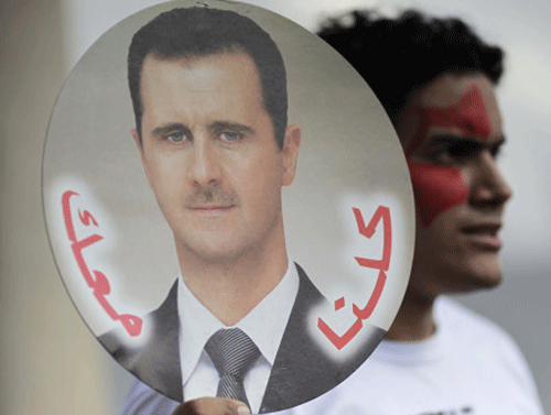 A student holds a sign with a picture of Syria's President Bashar al-Assad during a protest by a students' national union against possible U.S. military action in Syria, in Brasilia September 6, 2013. The sign reads, 'Against Imperialist War, Peace in Syria'. REUTERS