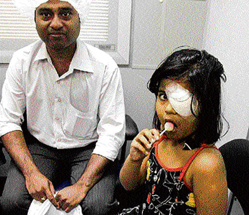 Sneha, 6, licks a candy as she sits beside her father after receiving laser treatment on her eye onboard the Orbis flying eye hospital in Kolkata on Tuesday. AP