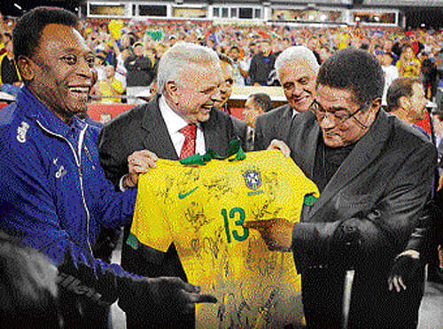starry touch Football greats Pele (left) and Eusebio (right) sign a Brazil jersey in Boston on Tuesday. reuters