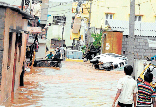 Waterworld: Residents watch vehicles floundering in rising water at a neighbourhood in Hiriyur. dh photo