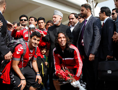 Afghan President Hamid Karzai poses with members of the national soccer team a day after they beat India 2-0 in the South Asian Football Federation Championship in Kabul, Afghanistan, Thursday, Sept, 12, 2013. Afghans welcomed home their national soccer team with exuberance and joy, a day after the squad won the war-weary country its first international trophy in the sport.AP Photo