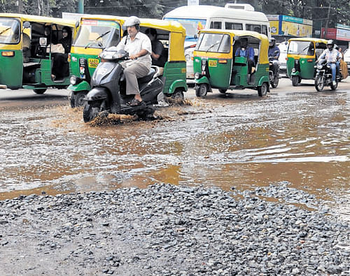 semblance of roads:   Motorists struggle to navigate a flooded road at Vellara Junction. dh Photo