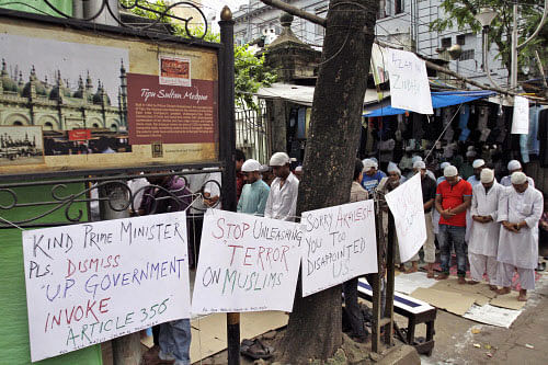 Muslims pray next to placards hanging on a thin string before a protest against the recent communal violence in the town of Muzaffarnagar in Uttar Pradesh state, in Kolkata, India, Friday, Sept. 13, 2013. The protest was organized by All India Majlis Falah-ul Muslimeen, a Muslim political party, demanding immediate resignation of Chief Minister of Uttar Pradesh state Akhilesh Yadav and the need of presidential rule in the state. (AP Photo