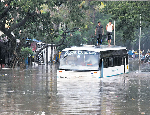 stranded: A KSRTC&#8200;bus was stranded on the Shantinagar main road which was flooded due to an overflowing drain in Davangere on Sunday. (Below) A house which collapsed due to rain at Jalalnagar in Raichur on Sunday morning. dh Photos