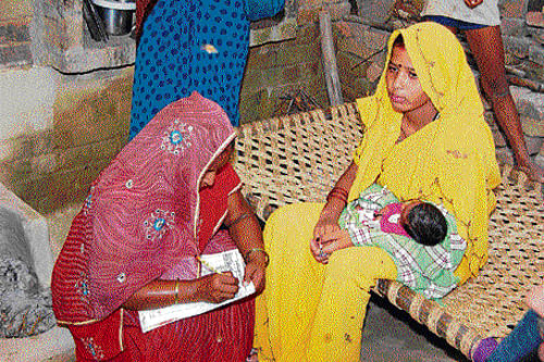 Pics: liec21INDm911c  An ASHA worker fills up forms during a home visit in Dhanipur block in Aligarh to keep records on the progress of a new born and mother.