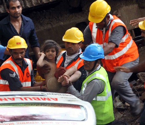 Rescue workers carry a girl towards an ambulance after she was pulled out from the rubble of a building that collapsed in Mumbai, India, Friday, Sept. 27, 2013. The apartment building collapsed in India's financial capital of Mumbai early Friday, killing people and sending rescuers racing to reach dozens of people trapped in the rubble. (AP Photo