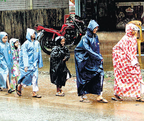 Children, some wearing raincoats on their way to schools at Kajubagh in Karwar on Friday morning. dh photo