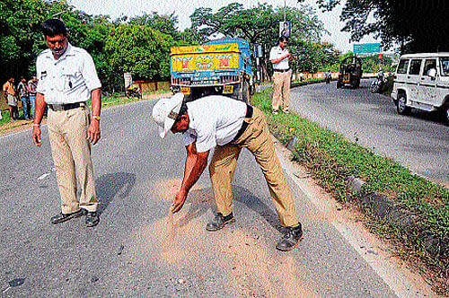 tragedy: Police cover blood stains with mud after the accident on Mysore-Hunsur road that claimed the life of Manu (Inset Mys 48), on Saturday. DH Photo