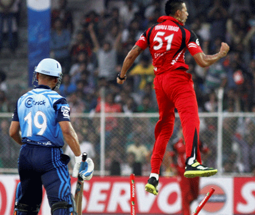 Titans team players Henry Davids is bowled out by Trinidad & Tobago blower Rayad Emrit (R) during their match at Champions League Twenty20 in Ahmedabad on Monday. PTI Photo