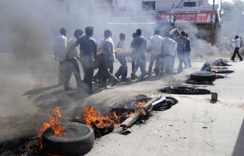 Protesters carry a wooden log past burning tyres during a protest against the creation of Telangana state, in Ananthapuram district in Andhra Pradesh. Reuters