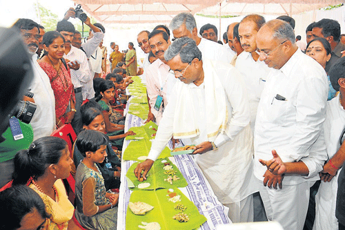 CM Siddaramaiah serves food to girls of Balamandira, in Mysore, on Saturday, during inauguration of Dasara Food Mela. DH Photo