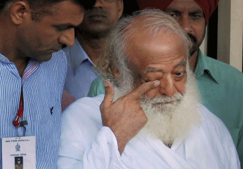 Asaram Bapu, arrested from his Indore ashram in connection with a sesual assault case, is escorted by the police at the airport in Jodhpur. PTI Photo