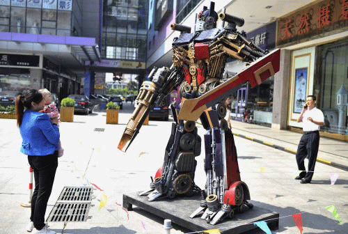 A woman holding a baby looks at a giant robot displayed on a street to promote a robot exhibition in Hefei. Reuters