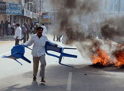 A supporter of United Andhra Pradesh shouts as he carries chairs to throw at police during a protest. AP Photo