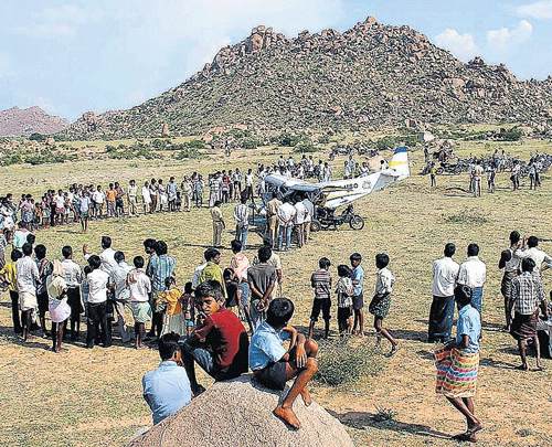 Residents look at the aircraft that made an emergency landing at Kurugodu in Bellary district on Monday.  KPN